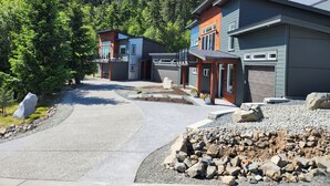 Un quartier résidentiel moderne comprenant deux maisons, une allée et un paysage boisé en arrière-plan.