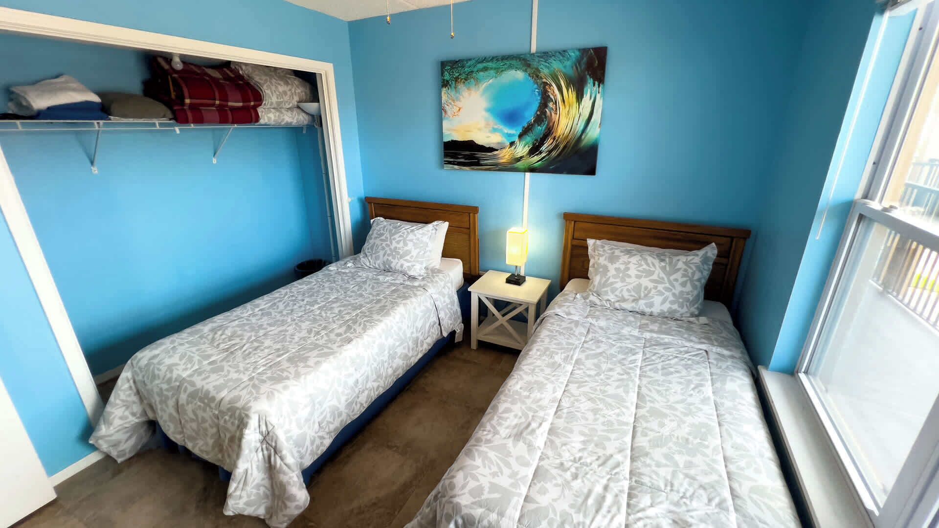 A room with two beds, a painting, and a window.