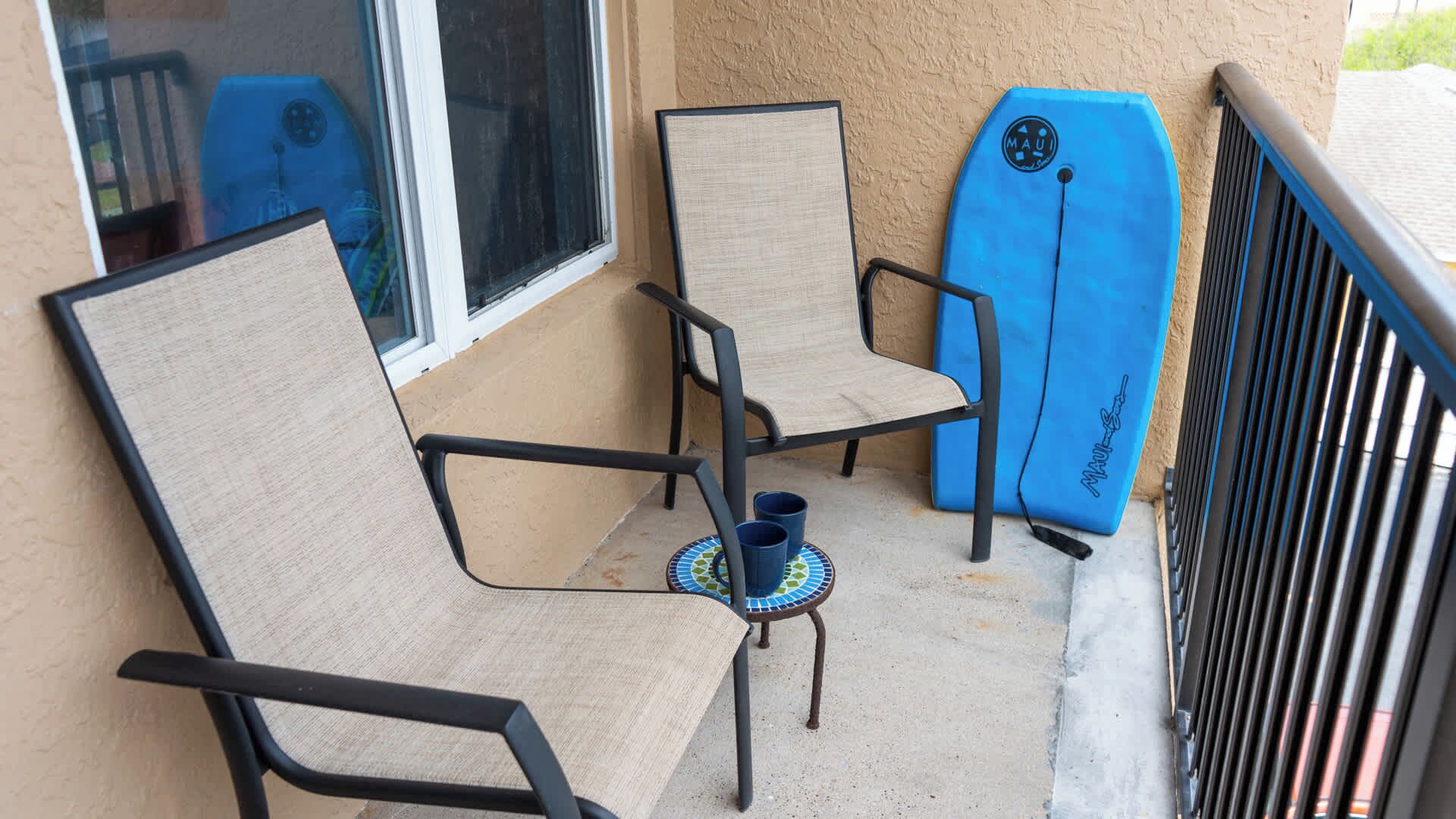 Un balcon avec deux chaises et une planche de surf.