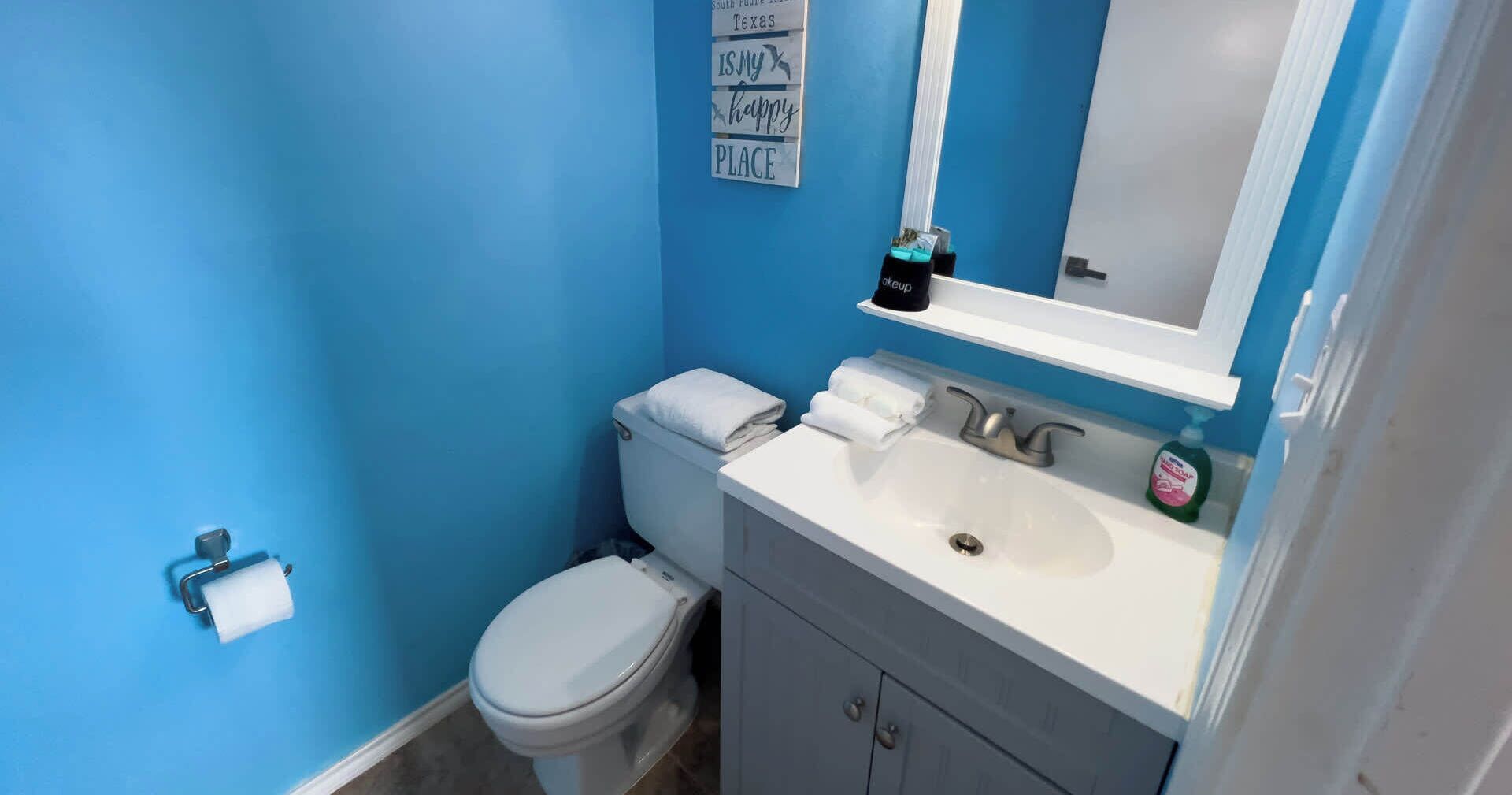 Un baño con inodoro, lavamanos y espejo.