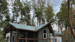Uma cabana com telhado de metal, deck de madeira e varanda coberta.
