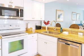 A modern kitchen with white cabinets, stainless steel appliances, a granite countertop, and a sink. - Surfside II 109 (South Padre Island)