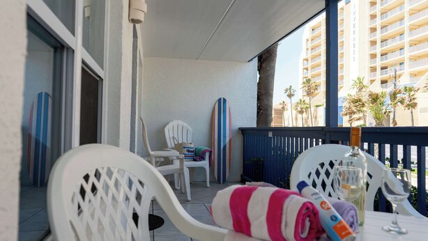 A balcony with white chairs, a striped towel, and a bottle of wine. - Updated - Comfy Inside - Beach 50 Yards Away (South Padre Island)