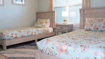 Un dormitorio con dos camas, cada una con ropa de cama estampada, una mesita de noche y una lámpara.