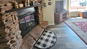 Una sala de estar con chimenea de piedra, televisor de pantalla plana y alfombra de diseño rojo y blanco.