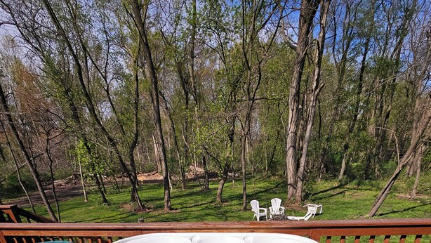 Un jacuzzi en una terraza con vistas a un área verde y árboles.