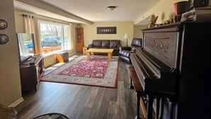 Una sala de estar con un piano, un sofá, una mesa de centro y un tapete rojo y blanco.
