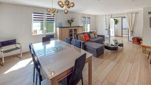 Ein geräumiger Wohnbereich mit Esstisch, Sofas und einer modernen Deckenleuchte.