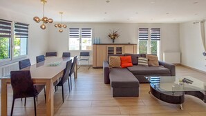 Ein modernes Wohnzimmer mit Essbereich, einer Sofagarnitur und einem Glastisch.