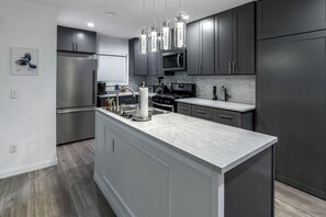 Una cocina moderna con armarios oscuros, electrodomésticos de acero inoxidable y una isla central.