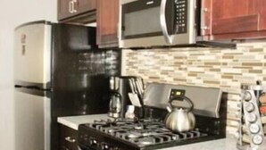 A modern kitchen with dark wood cabinets, stainless steel appliances, and a tiled backsplash.