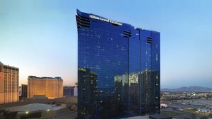 A modern high-rise hotel with a glass facade, named Hilton Grand Vacations, featuring a prominent rooftop structure and a view of the surrounding cityscape. - Elara Studio (Las Vegas)