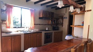 Une cuisine avec des meubles en bois, un grand îlot central et une fenêtre ornée de rideaux rouges.