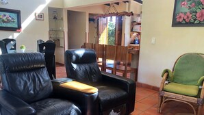 Un salon avec des fauteuils en cuir, un fauteuil vert et une table basse avec un plateau en verre.
