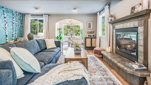 A cozy living room with a fireplace, a sofa, a coffee table, and a rug. - Hillside Cottage: Private Pond, Hot Tub, Game Room by Hurricane Ridge, ONP (Port Angeles)