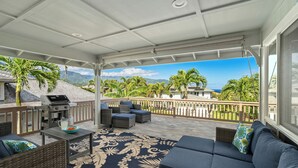 A covered outdoor area with a grill, wicker furniture, and a view of mountains and palm trees. - 4Br 4.5 Ba Punahele House with Ocean and Mountain Views, Beach Gear, Near Queens Pond (Princeville)