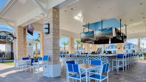 Un espace bar extérieur avec des sièges bleus et blancs, un pilier en pierre et une enseigne pour le Blue Marlin Grille.