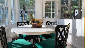 A dining area with a round table, four chairs, and a fruit basket.