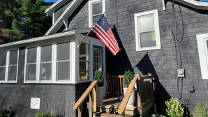 A house with a dark gray exterior, white trim, and a front porch with a wooden railing.