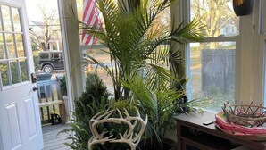 A room with a wooden chair, a potted plant, a fireplace, and a view of the outside.