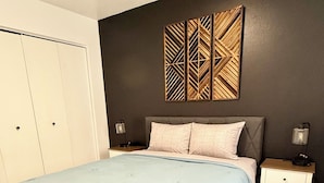A bedroom with a bed, nightstands, a wardrobe, and a decorative wall panel. - Restful Nest A 3bd&2ba in Midtown Anchorage (Anchorage)