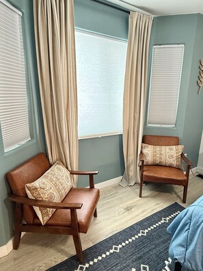 A room with two leather armchairs, a patterned rug, and a window with a curtain.