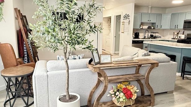 A living room with a sofa, a coffee table, a potted plant, and a small wooden table with a flower arrangement. - Restful Nest A 3bd&2ba in Midtown Anchorage (Anchorage)