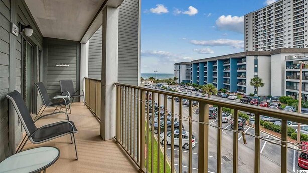 Un balcon avec des chaises et une vue sur un parking et des immeubles.