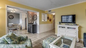 Un salon comprenant un canapé, une table basse, un téléviseur et un coin repas avec des chaises et une table.