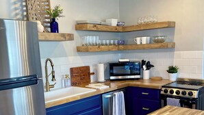 Una cocina moderna con un refrigerador de acero inoxidable, una encimera de madera, gabinetes azules, un microondas y una estufa.