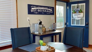 Un comedor con una mesa redonda, sillas azules, un letrero decorativo y una lámpara moderna.