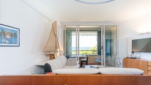 Een gezellige kamer met een bank, een klein tafeltje en een raam met uitzicht op zee.