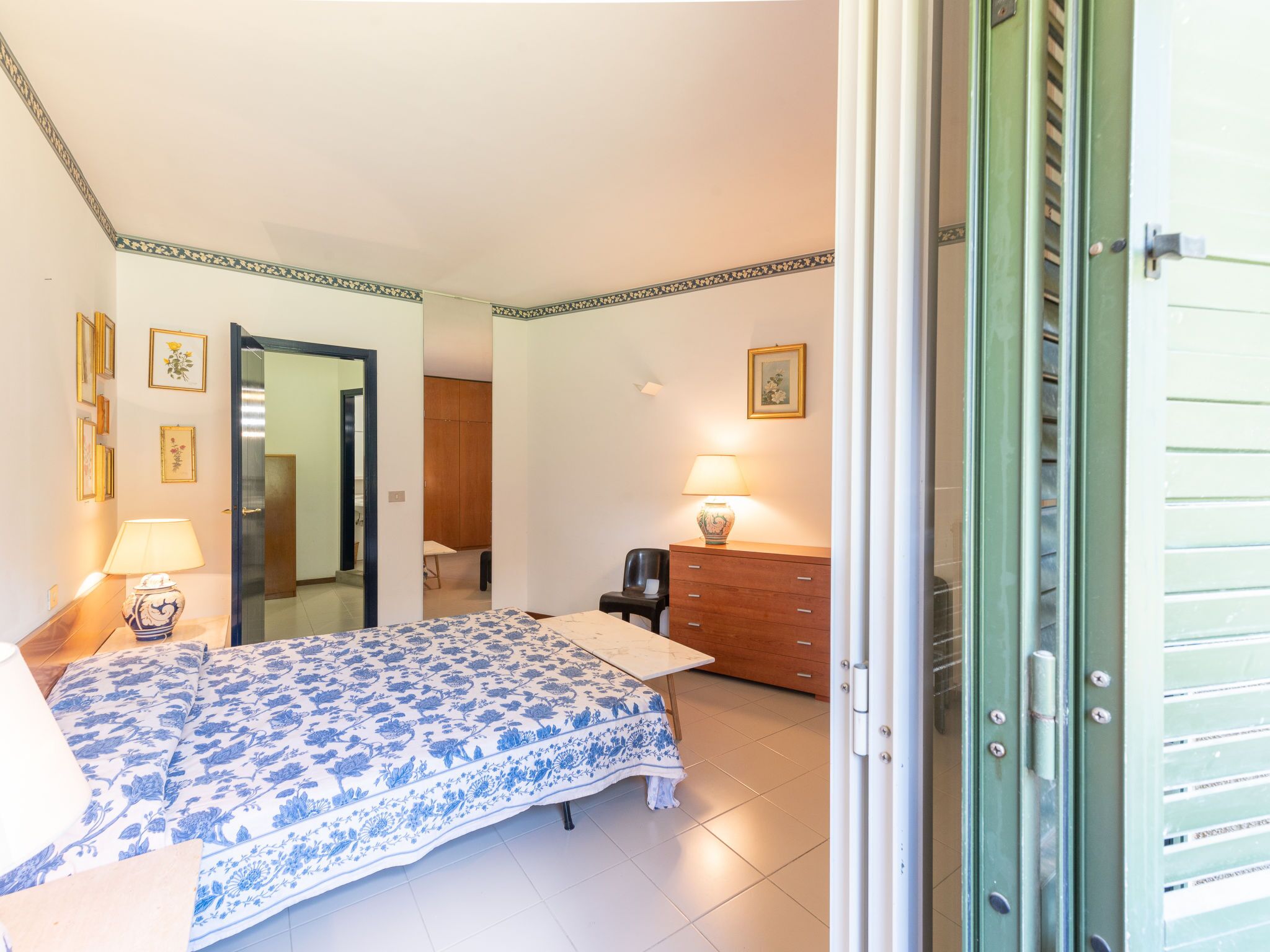 A bedroom with a bed, bedside lamps, a dresser, and a mirror.