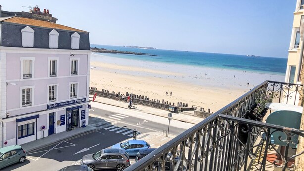 Un balcon donnant sur une plage, avec un bâtiment au premier plan.