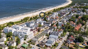 Vista aérea de un pueblo costero con playa, edificios residenciales y un muelle.