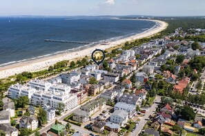 An aerial view of a coastal town with a beach, residential buildings, and a pier.