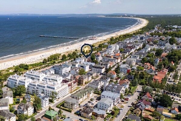 Vue aérienne d’une ville côtière avec une plage, des immeubles résidentiels et une jetée.