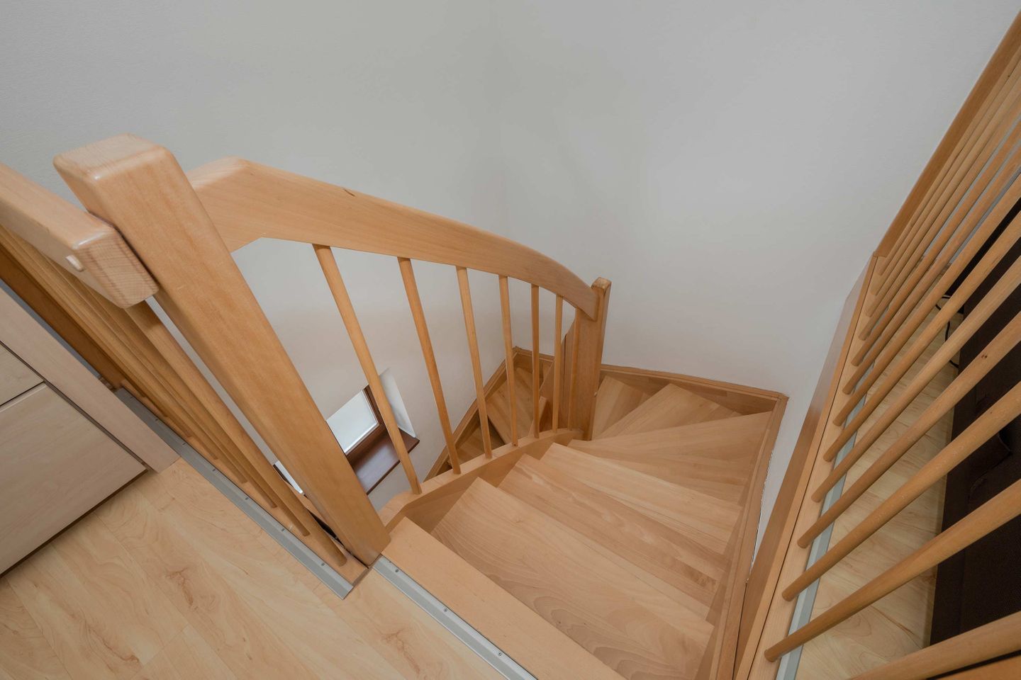 A wooden staircase with a handrail and a landing area.