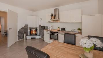 A modern kitchen with a built-in fireplace, a dining area with a table and chairs, and a kitchen island with appliances.