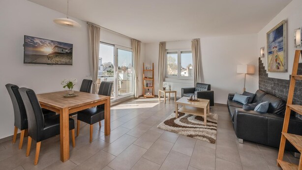 A modern living room with a dining area, a sofa, and a TV.