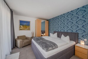 A bedroom with a bed, a chair, a bedside table, a nightstand, and a painting on the wall. - Komfortable, Gemütliche Fewo am Wolgastsee mit Wlan und Kamin. - Villa Petra (Korswandt)