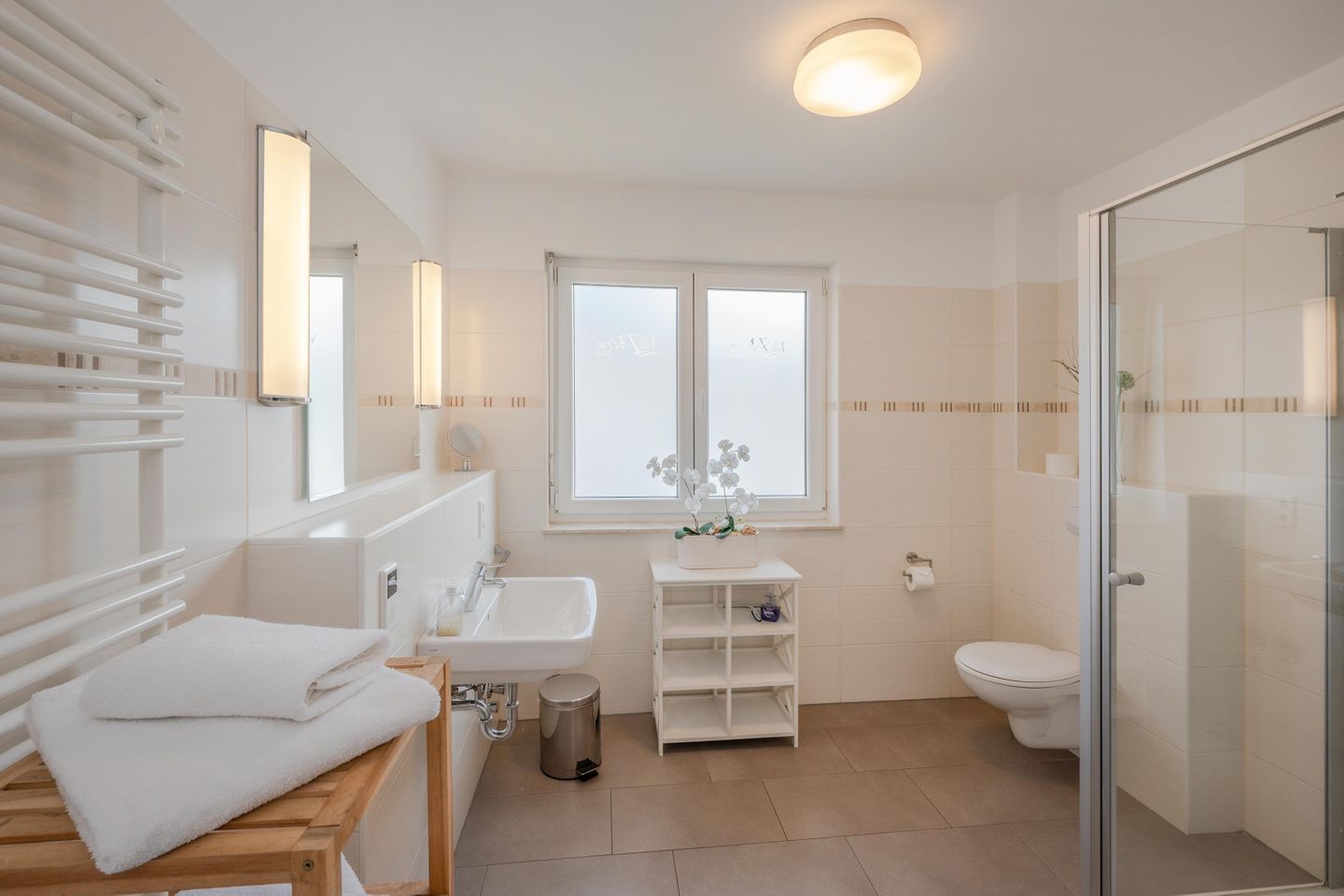 Ein modernes Badezimmer mit Badewanne, Waschbecken, Toilette und einer Duschkabine aus Glas.