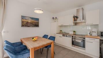 Een moderne keuken met witte kasten, een houten eettafel en blauwe stoelen.