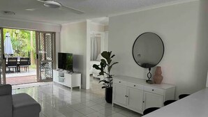 Un salon moderne avec un téléviseur, un canapé, une table à manger et une plante en pot.