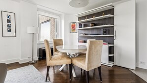 Un comedor moderno con una mesa redonda, cuatro sillas, una lámpara de pie y una estantería.