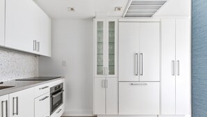 Una cocina moderna con armarios blancos, horno empotrado y extractor de acero inoxidable.