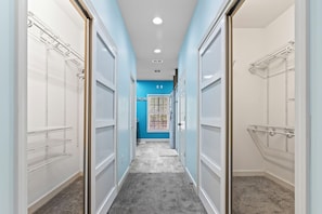 Functional hallway leading to a room with a blue accent wall and ample storage space.