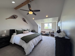 Quarto com cama, ventoinha no teto, janela, sofá e cómoda.