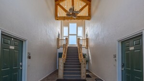 Gradi que condueixen a un segon pis, amb sostre de fusta i una porta verda a l'esquerra.