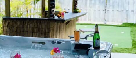 Uma banheira de hidromassagem com duas bebidas, uma garrafa e decorações tiki.
